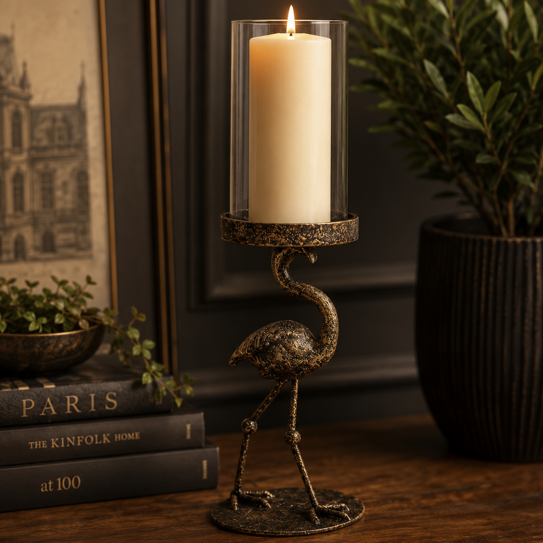 Decorative candle holder with a lit candle on a wooden surface, surrounded by books and a plant.